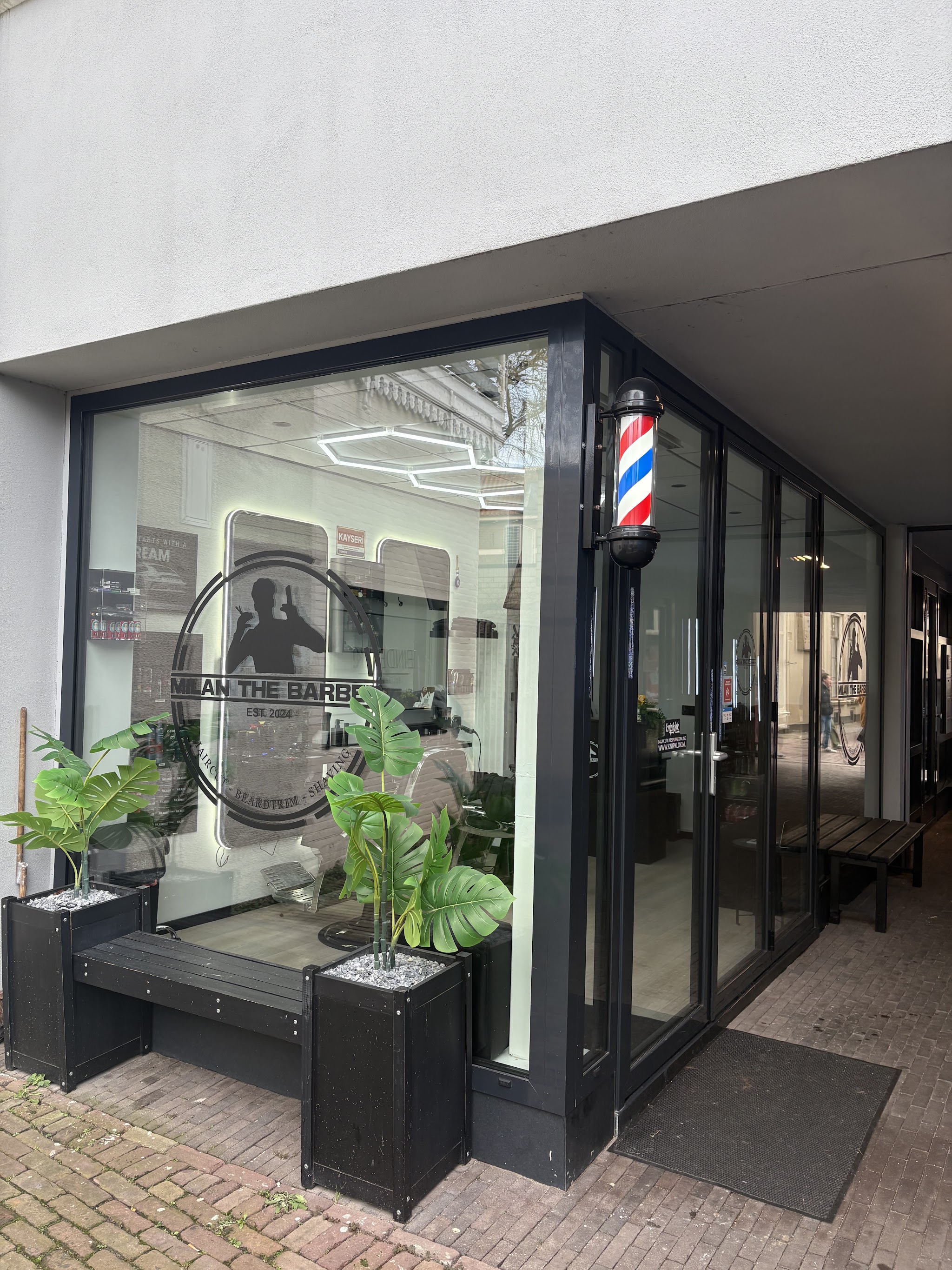 De zaak van MilanTheBarber in de Proosdijpassage, met de barberpaal naast de deur en het logo op het raam