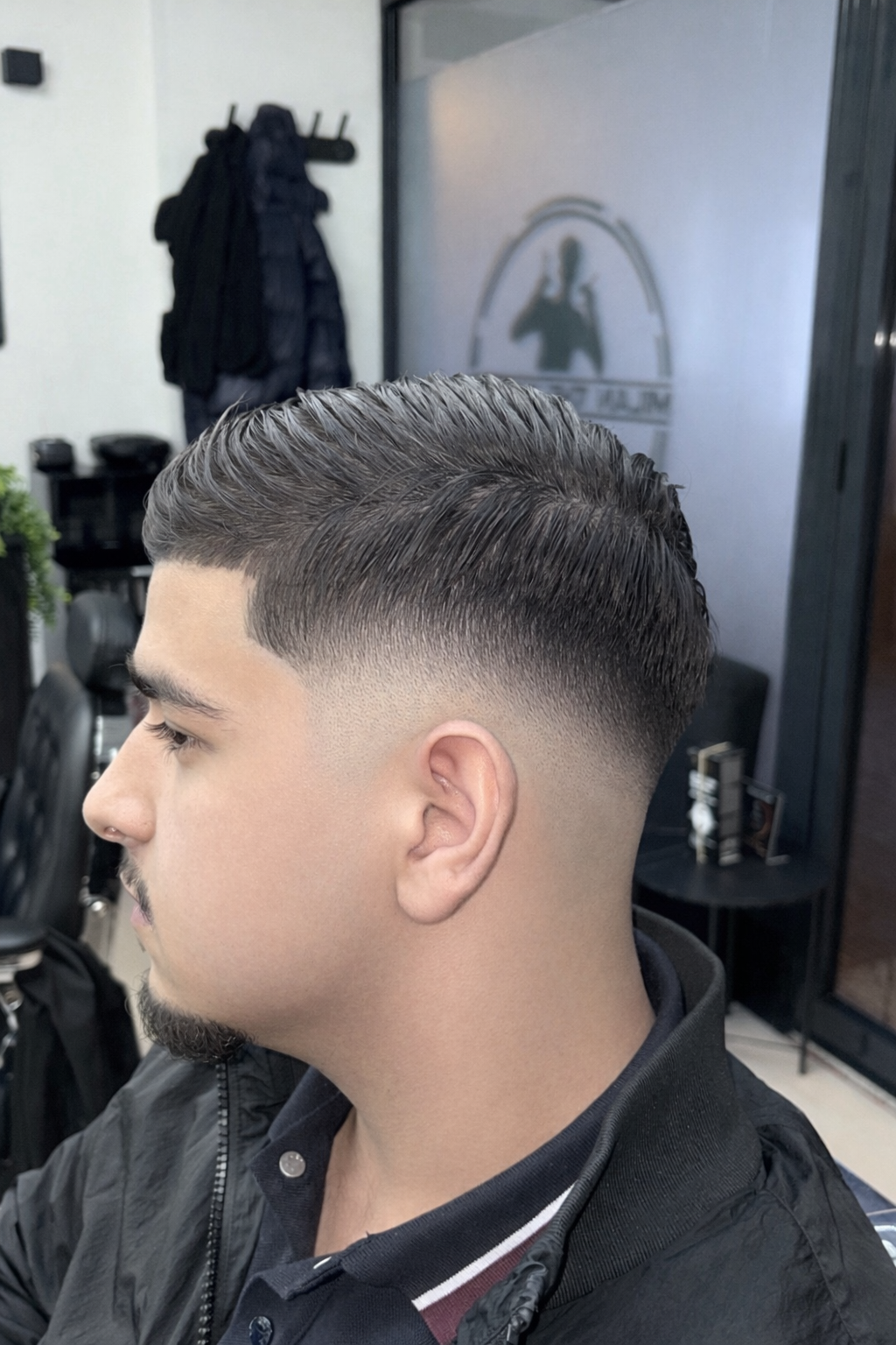 Skin fade van opzij, met het logo op het raam op de achtergrond