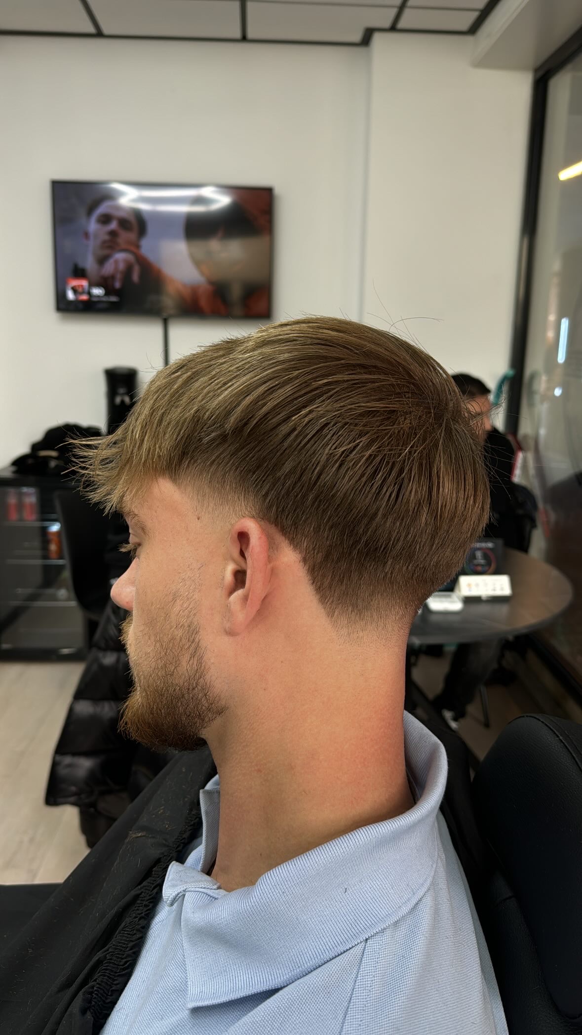 Taper fade met lang bovenhaar, in de zaak